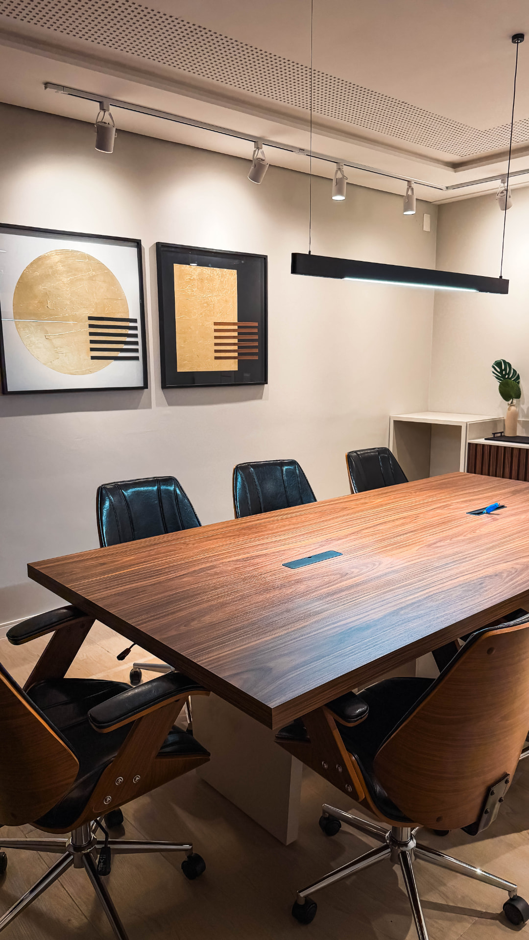 Sala de reunião com mesa de madeira e cadeiras em couro